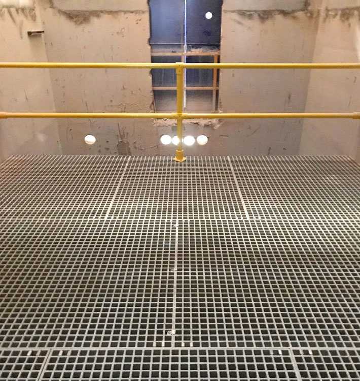 Installed GRP grating riser floor with safety handrail.